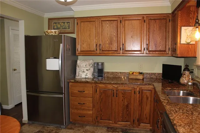 a kitchen with stainless steel appliances granite countertop a refrigerator a stove and a sink with wooden cabinets