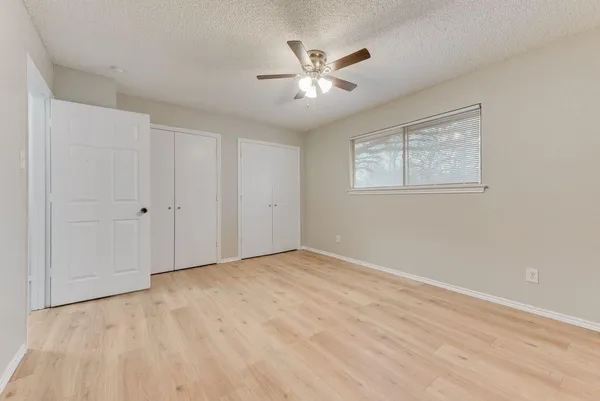 an empty room with wooden floor and ceiling fan