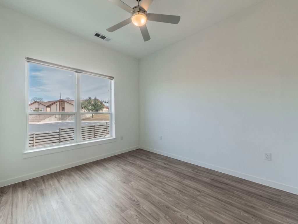 4901 Springdale Road, Unit 103 Austin, TX 78723 - Photo 20 of 26 an empty room with wooden floor fan and windows