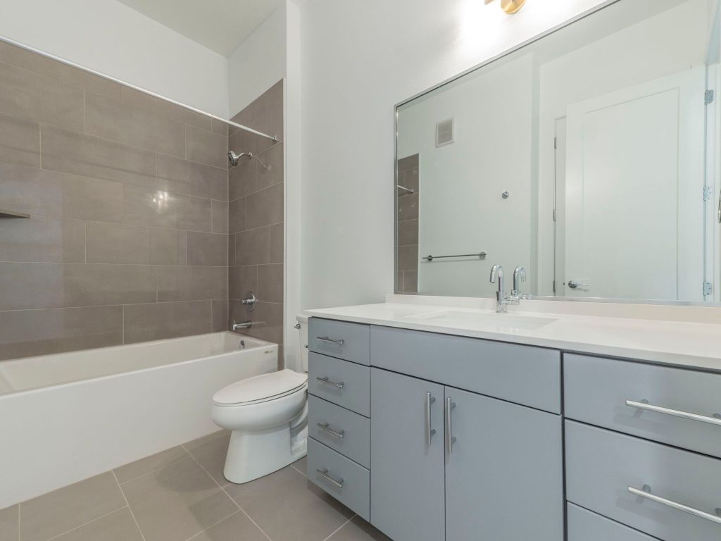 4901 Springdale Road, Unit 103 Austin, TX 78723 - Photo 22 of 26 a bathroom with a sink a toilet and a large mirror