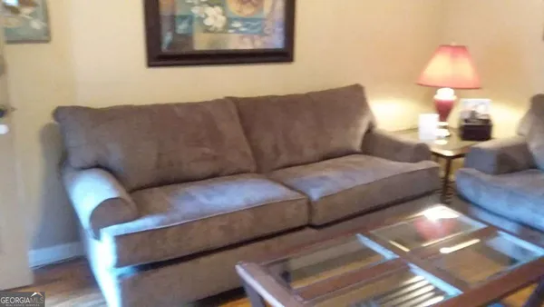 a living room with couches painting on the wall and a lamp on table