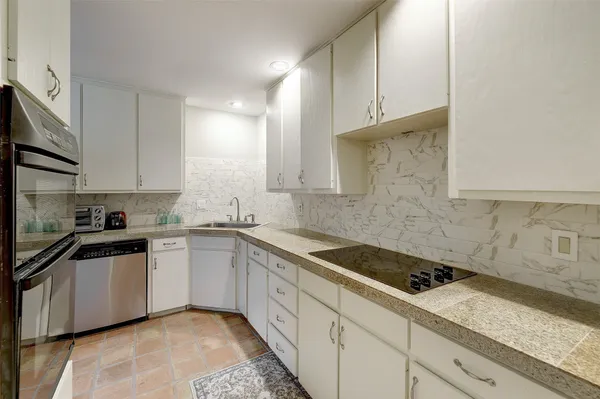 a kitchen with granite countertop a sink a stove and cabinets