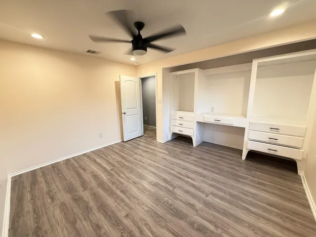 a view of kitchen and empty room with wooden floor