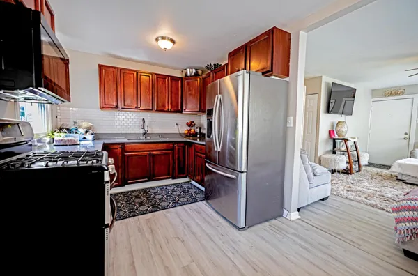 a kitchen with stainless steel appliances granite countertop a refrigerator a stove top oven a sink dishwasher and wooden floor