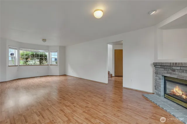 an empty room with wooden floor fireplace and windows