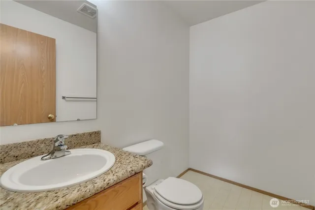 a bathroom with a granite countertop sink toilet and a mirror