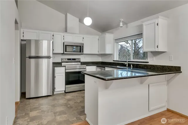 a kitchen with granite countertop a sink stove and refrigerator