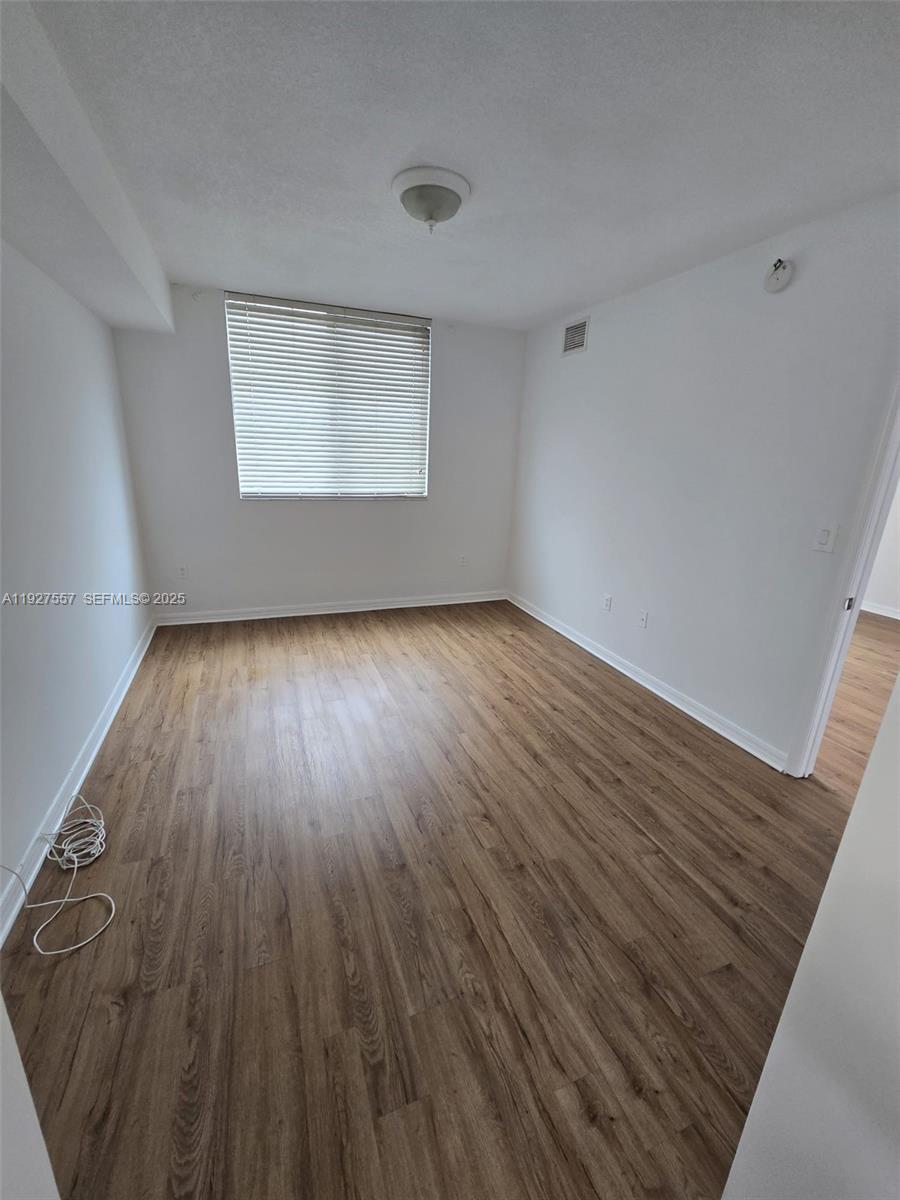 4242 Northwest 2nd Street, Unit 1614 Miami, FL 33126 - Photo 12 of 24 a view of an empty room with wooden floor and a window