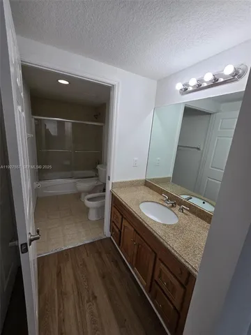 a bathroom with a granite countertop sink a toilet and a mirror