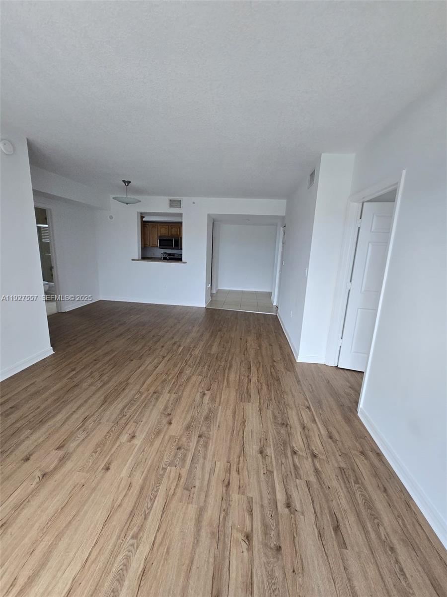 4242 Northwest 2nd Street, Unit 1614 Miami, FL 33126 - Photo 6 of 24 a view of a big room with wooden floor and a window