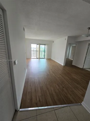 a view of an empty room with wooden floor and stairs