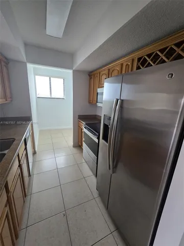 a kitchen with granite countertop a refrigerator and a stove top oven