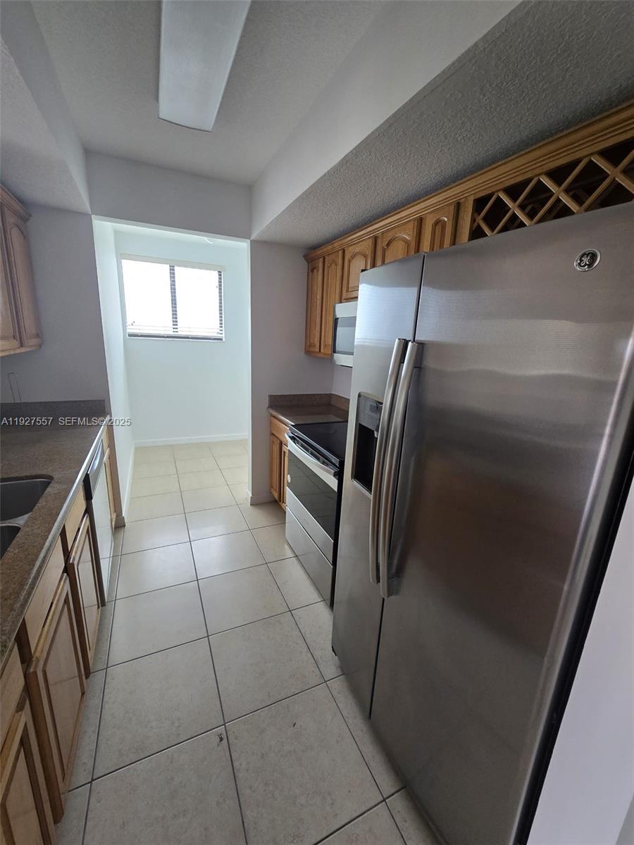 4242 Northwest 2nd Street, Unit 1614 Miami, FL 33126 - Photo 10 of 24 a kitchen with granite countertop a refrigerator and a stove top oven