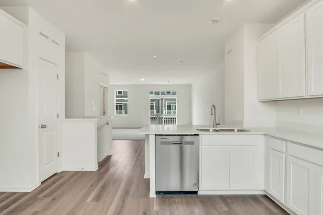 a kitchen with stainless steel appliances white cabinets and wooden floors