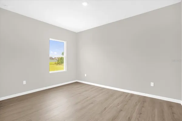 a view of an empty room with a window and wooden floor