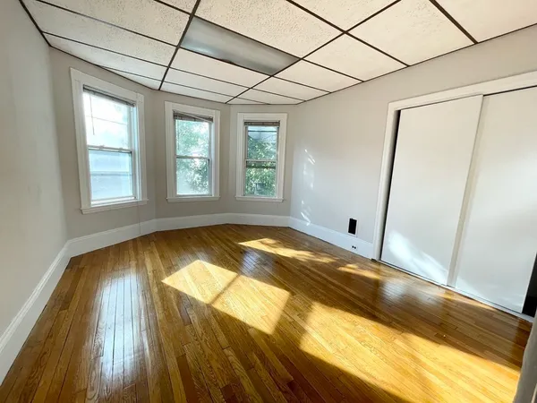 a view of an empty room with a window and wooden floor