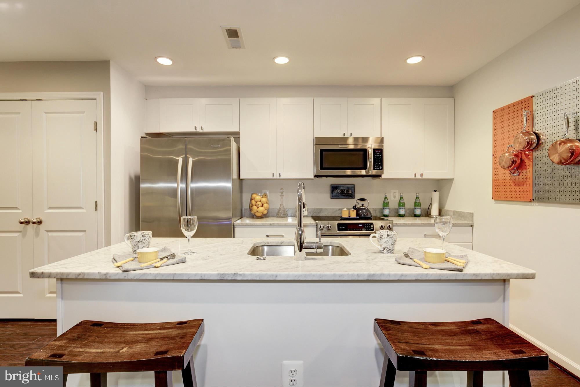 1845 Kalorama Road Northwest, Unit 1 Washington, DC 20009 - Photo 5 of 20 a kitchen with a sink a microwave a refrigerator and chairs