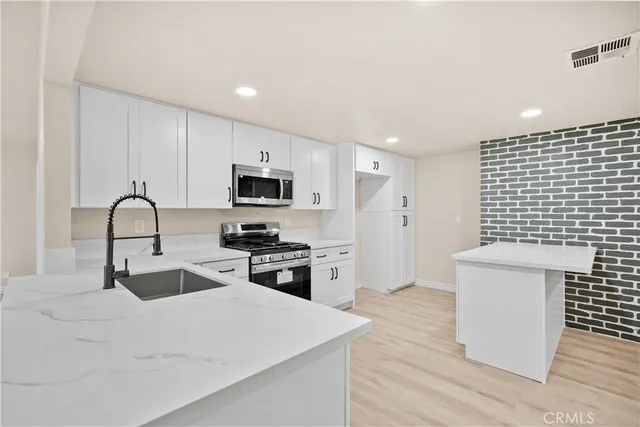 a kitchen with granite countertop a sink stove and refrigerator