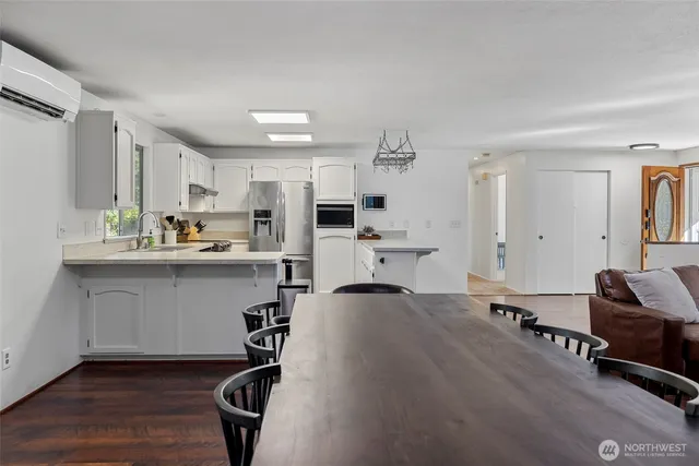 a living room with stainless steel appliances furniture and a wooden floor