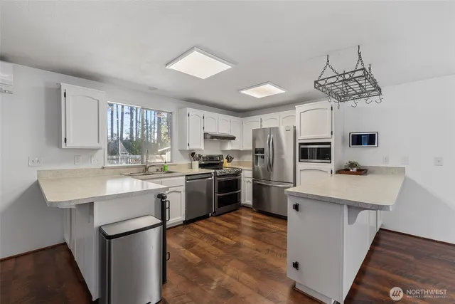 a kitchen with a sink a counter top space stainless steel appliances and cabinets