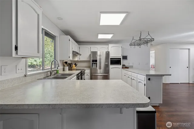 a large kitchen with stainless steel appliances a large counter top a stove a chimney a sink and a large window