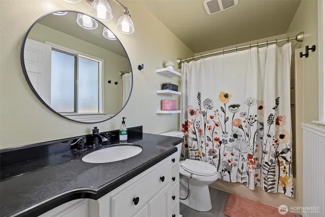 a bathroom with a granite countertop sink vanity mirror and toilet