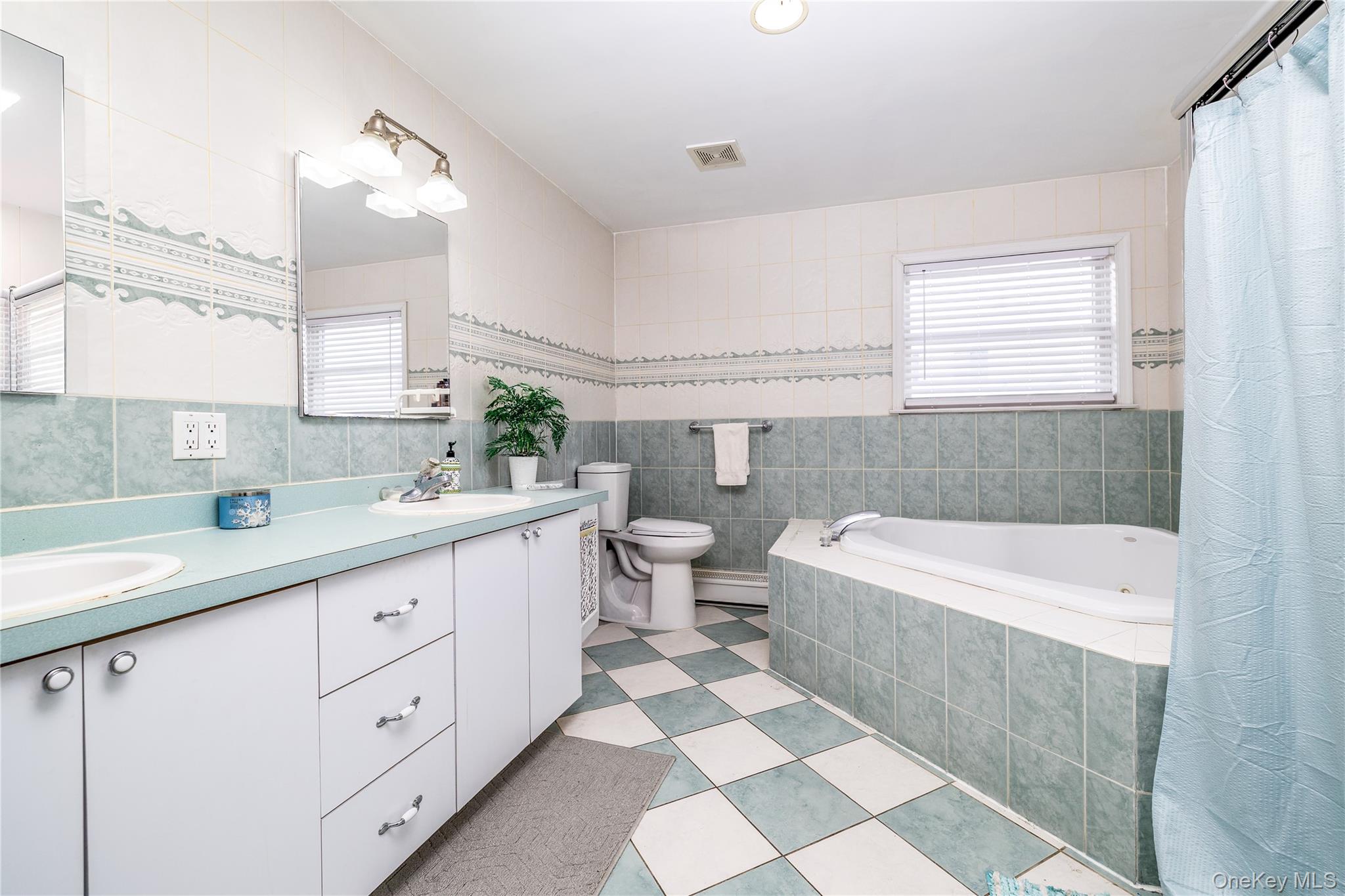 458 East Pine Street Long Beach, NY 11561 - Photo 19 of 26 a bathroom with a double vanity sink a toilet a mirror and bathtub