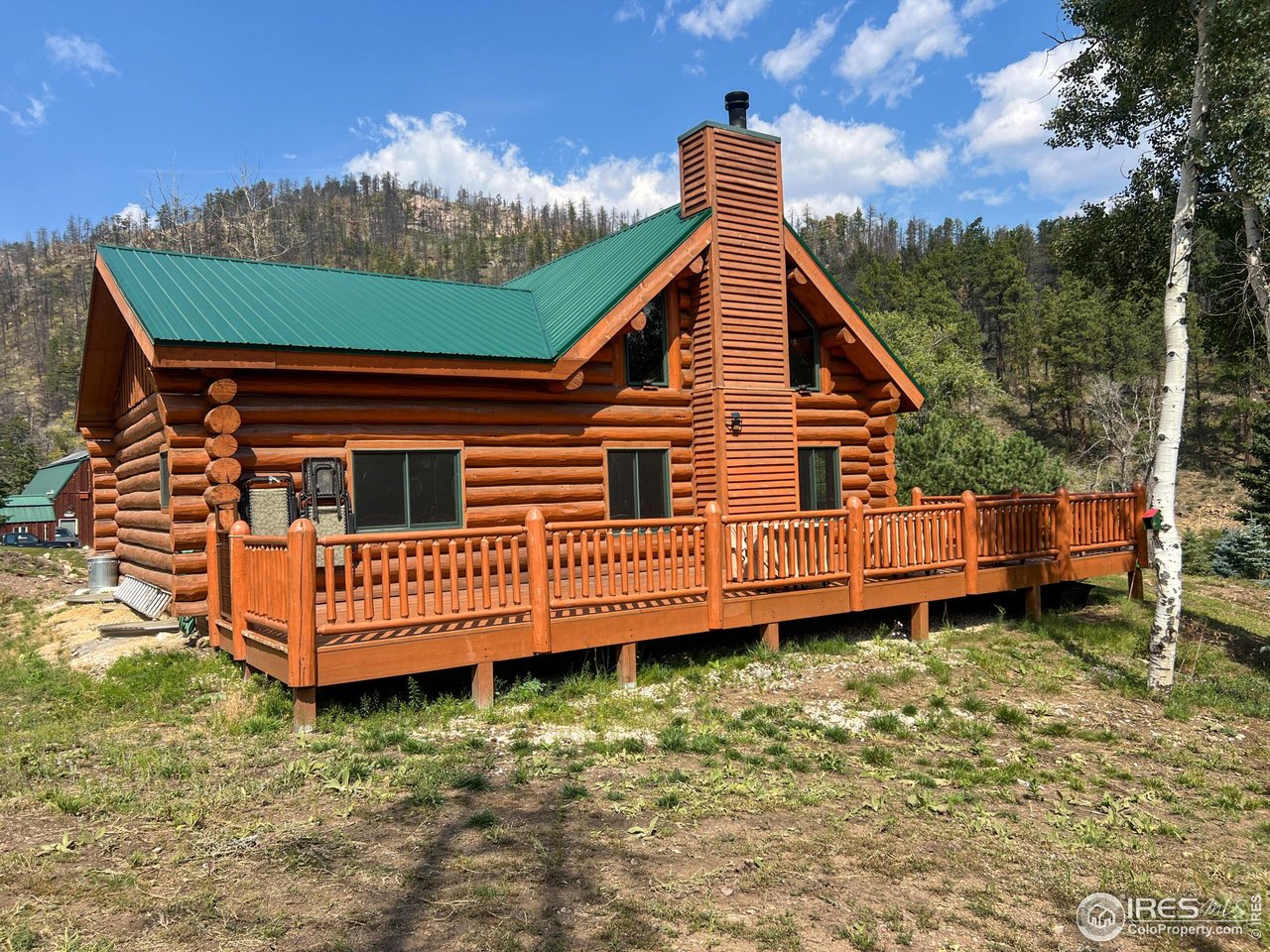 27667 Buckhorn Road Bellvue, CO 80512 - Photo 5 of 40 a view of a house with a wooden deck and a yard