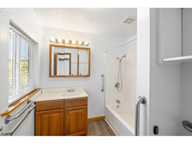 a bathroom with a granite countertop sink a mirror a bathtub and shower