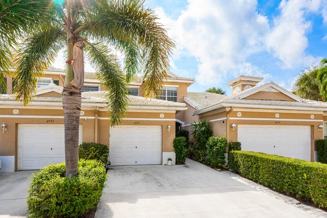 a front view of a house with a yard and palm trees