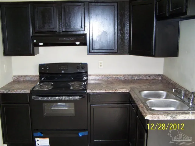 a kitchen with granite countertop stainless steel appliances stove top oven and cabinets