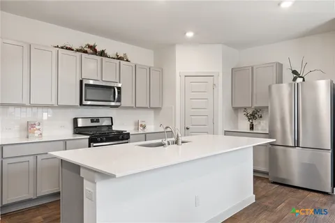 a kitchen with kitchen island a sink appliances and cabinets