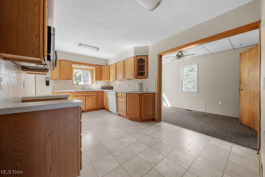 1702 Far View Road Akron, OH 44312 - Photo 9 of 49 Kitchen with healthy amount of natural light, glass insert cabinets, light tile patterned floors, light carpet, and a textured ceiling