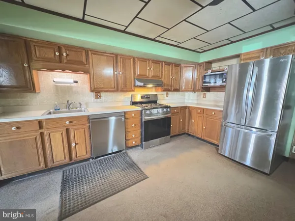 a kitchen with stainless steel appliances granite countertop a sink stove refrigerator and cabinets
