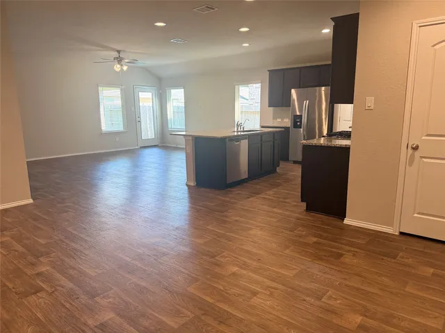 a view of a kitchen with refrigerator and wooden floor
