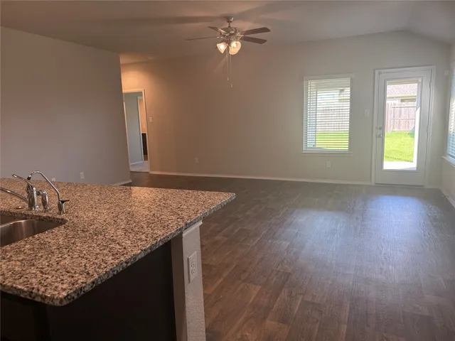 a kitchen with granite countertop a sink cabinets and wooden floor