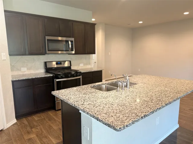 a kitchen with granite countertop kitchen island stainless steel appliances sink microwave and stove