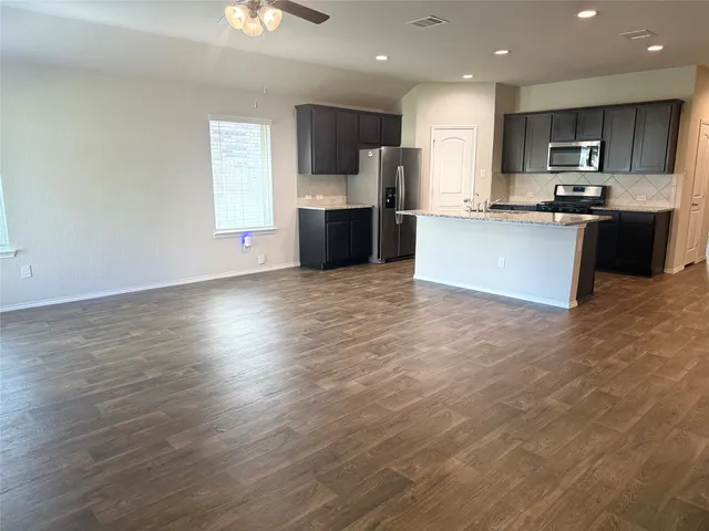 a large kitchen with stainless steel appliances granite countertop a large counter top a sink and a stove