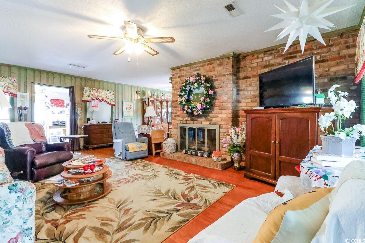 404 13th Avenue South Myrtle Beach, SC 29577 - Photo 2 of 39 Living room featuring a ceiling fan, a fireplace, wood finished floors, and brick wall