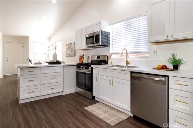 a kitchen with stainless steel appliances a sink dishwasher stove refrigerator and microwave with wooden floor