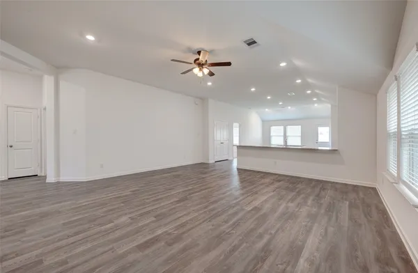 an empty room with wooden floor and windows