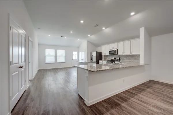a kitchen with stainless steel appliances granite countertop wooden cabinets granite counter tops and a hard wood floors
