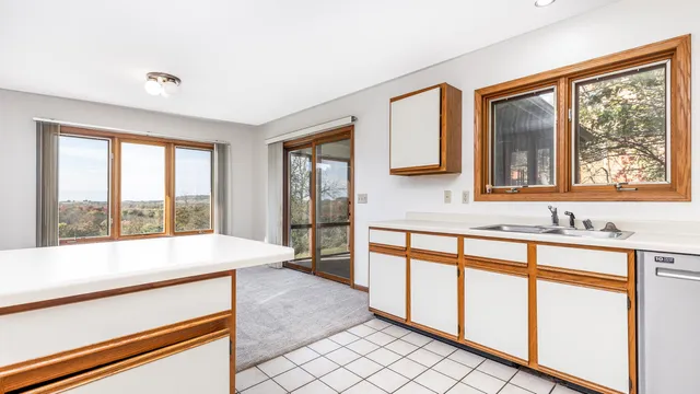 a large white kitchen with a large window sink and cabinets