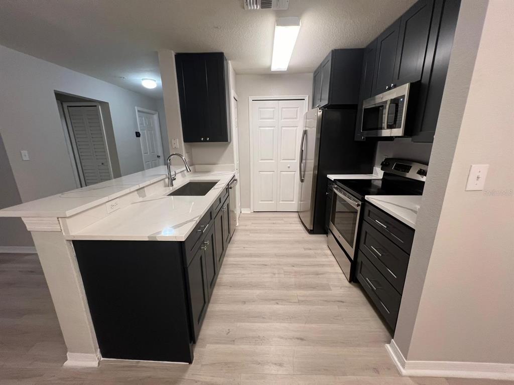 5455 Vineland Road, Unit 3108 Orlando, FL 32811 - Photo 8 of 17 a kitchen with stainless steel appliances a sink stove and refrigerator
