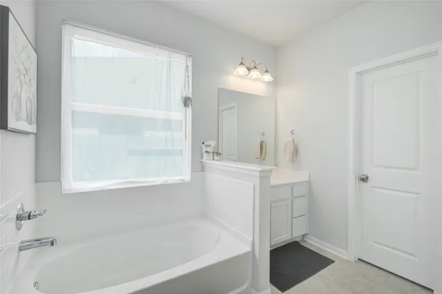 a bathroom with a bathtub a mirror a vanity and a shower