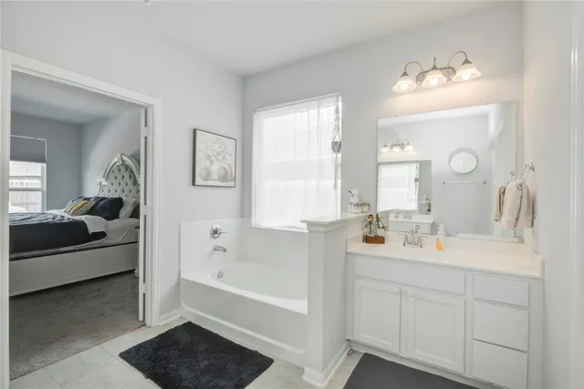 a bathroom with a tub double sink window and mirror