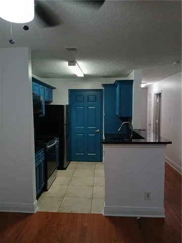 a kitchen with granite countertop a refrigerator and a stove top oven