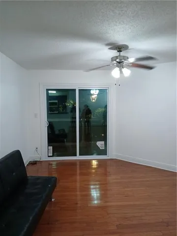 a view of a livingroom with wooden floor a ceiling fan and front door