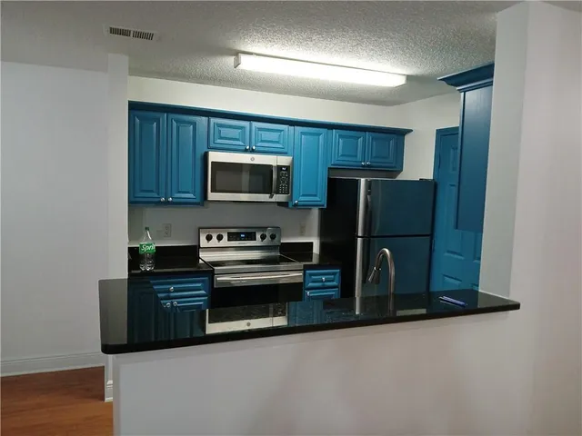 a kitchen with a refrigerator a microwave a sink and cabinets