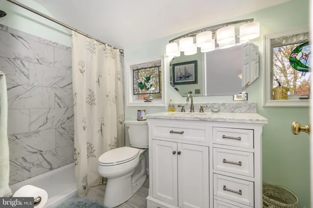 a bathroom with a granite countertop sink toilet a mirror a vanity and shower
